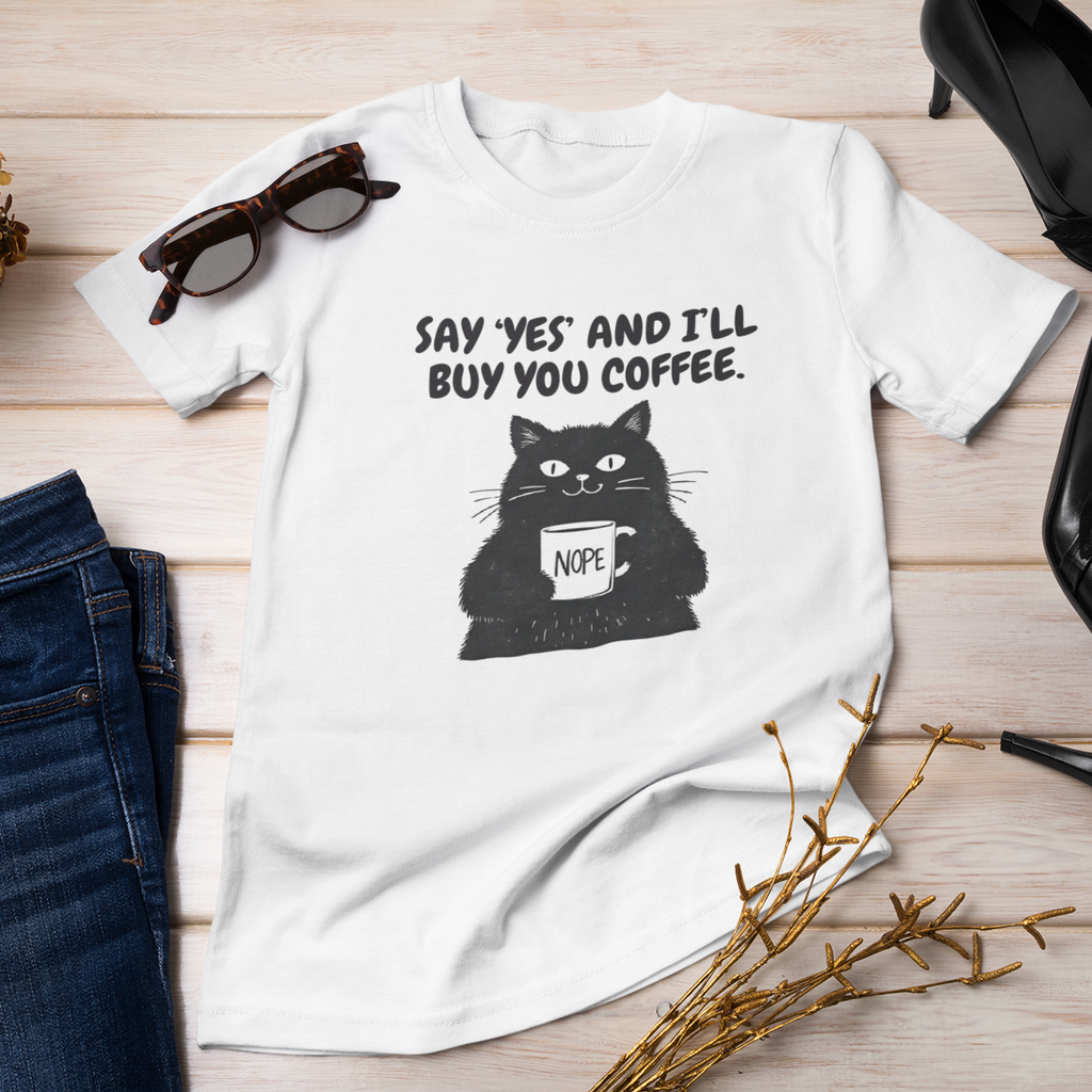 White t-shirt with a cat graphic and text, paired with jeans, sunglasses, and high heels on a wooden surface.